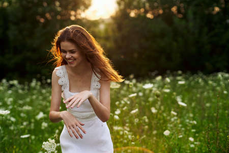 Woman in white dress in a field flowers sun nature freedomの写真素材