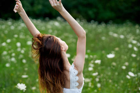 Woman in white dress in a field of flowers walk freedomの写真素材