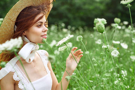 Woman in white dress and hat in a field with flowers lifestyleの写真素材