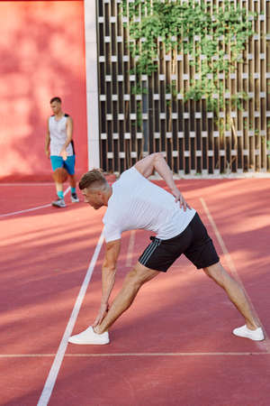 athletic men doing exercises on the sports ground in summerの写真素材