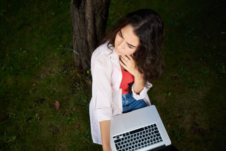 woman outdoors sitting on the grass business technologyの写真素材