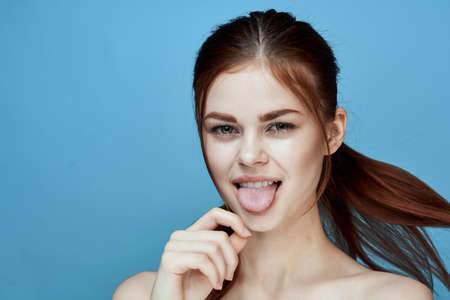 woman with bared shoulders pigtail emotions posing blue backgroundの写真素材