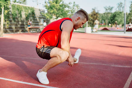 sports man in a red t-shirt on the sports ground doing exercisesの写真素材