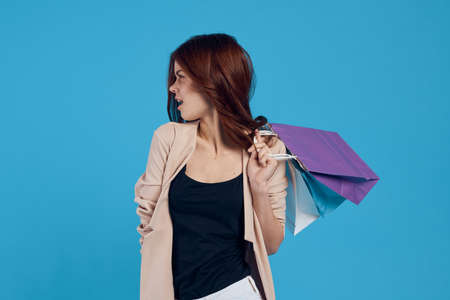 beautiful woman with multicolored bags posing blue backgroundの写真素材