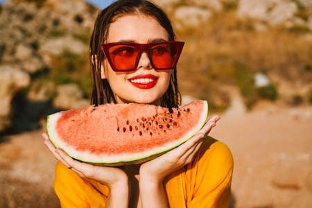 woman on the beach near the ocean eating watermelonの写真素材