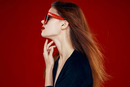 pretty woman wearing sunglasses fashion posing hairstyle red backgroundの写真素材