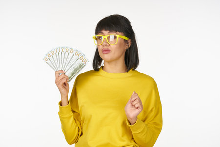 woman in a yellow sweater with money in her hands fun wealth