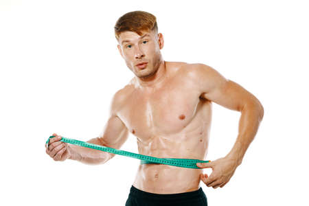 athletic man with measuring tape muscle workoutの写真素材