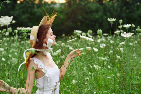 Woman in white dress and hat in a field with flowers lifestyleの写真素材