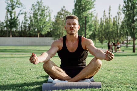 sporty man sitting on the lawn in the park trainingの写真素材