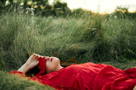 woman in red dress lying on the grass fresh air nature romanceの写真素材