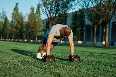 athletic man training with dumbbells in the morning Parkの写真素材