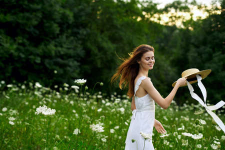 Woman in white dress hat nature field flowersの写真素材