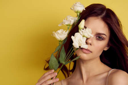 cheerful woman flowers in hands posing charm yellow backgroundの写真素材