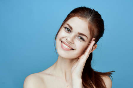 woman with bared shoulders pigtail emotions posing blue backgroundの写真素材