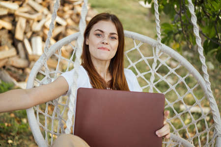 cheerful woman outdoors in hammock with laptop restの写真素材