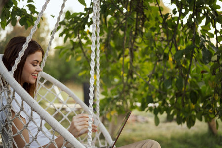 woman with laptop outdoors resting in hammock internet