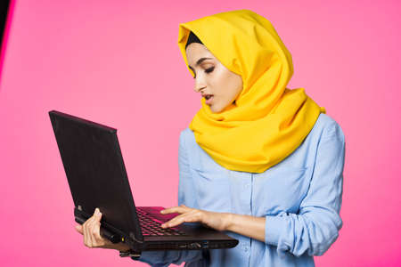 cheerful muslim woman in yellow hijab learning laptop technologyの写真素材