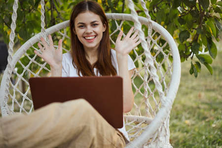 cheerful woman outdoors in hammock with laptop restの写真素材