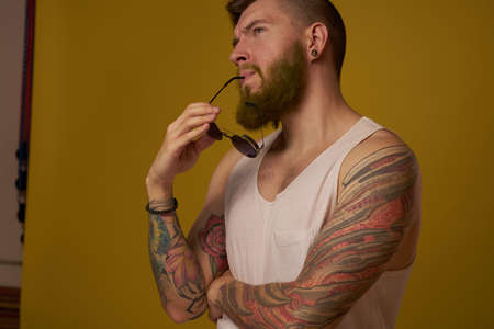 man in a white t-shirt tattoos on his arms fashion glasses modern styleの写真素材