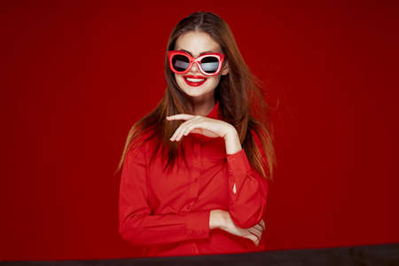 attractive woman in red shirt sunglasses fashion red backgroundの写真素材