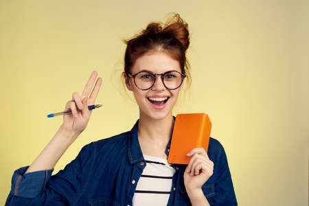 woman student with glasses notepad with pen yellow backgroundの写真素材