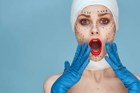beautiful woman posing in blue gloves red lips surgery facial rejuvenation isolated backgroundの写真素材