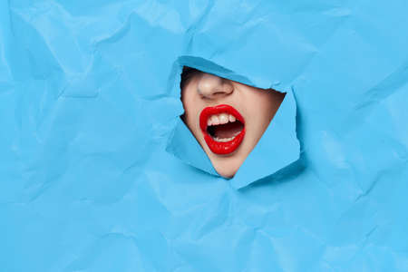womans face breaks through blue mockup close-upの写真素材