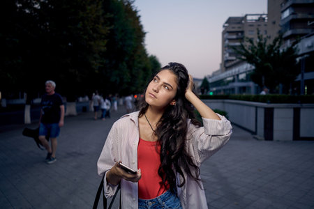 woman talking on the phone outdoors walking in the evening on the streetの写真素材