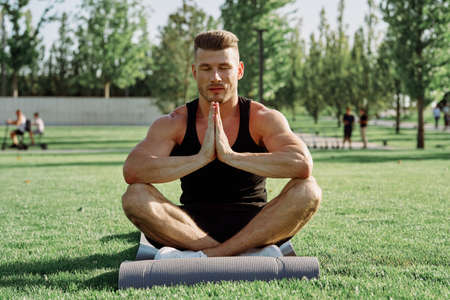 sporty man sitting on the lawn in the park trainingの写真素材