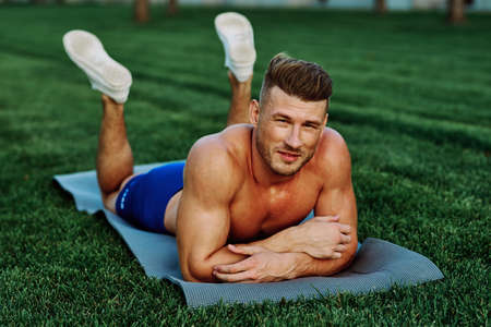 athletic man with pumped up muscular body in the park doing exerciseの写真素材