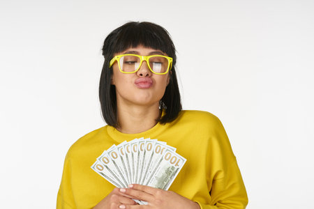 woman in a yellow sweater with money in her hands fun wealthの写真素材