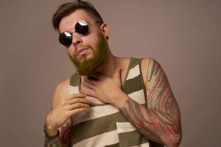 bearded man in striped t-shirt glasses tattoo on his arms fashionの写真素材
