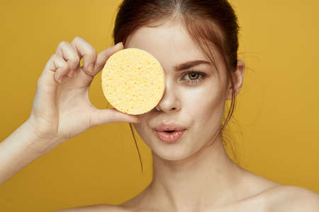 pretty woman with sponges in her hands bare shoulders clean skin hygieneの写真素材