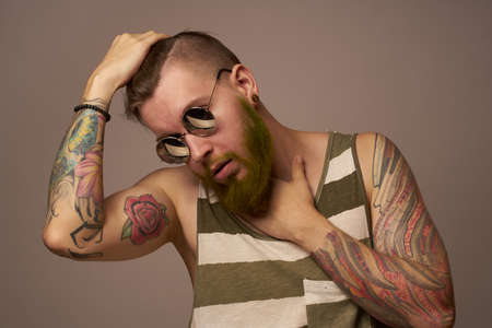 bearded man in striped t-shirt glasses tattoo on his arms fashionの写真素材