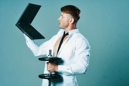 a man in a shirt with a pumped-up body laptop dumbbells business officeの写真素材