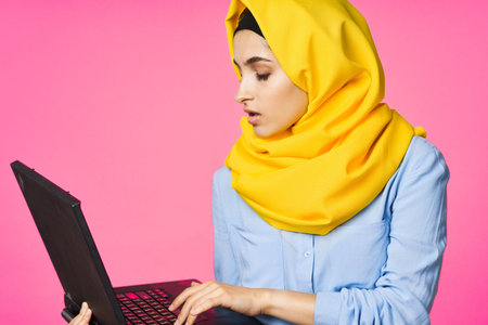 cheerful muslim woman in yellow hijab learning laptop technology