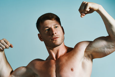 bodybuilder with muscular body posing press blue backgroundの写真素材