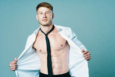 sporty man in unbuttoned shirt with muscle tie posingの写真素材