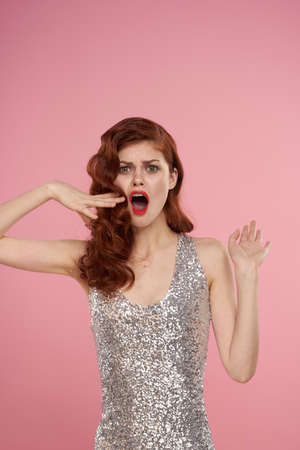 woman in a silver dress beautiful hairstyle bright makeup pink backgroundの写真素材