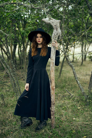 woman in witch costume in forest posing staff logic