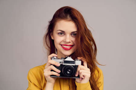 pretty woman photographer with camera in yellow shirt on blue backgroundの写真素材