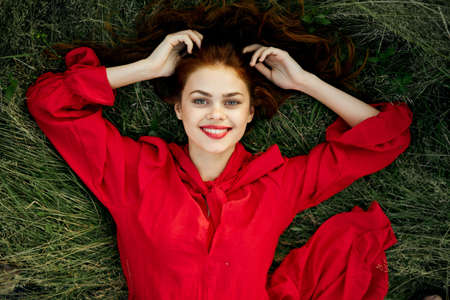 woman in a red dress lies on the grass fashion nature summerの写真素材