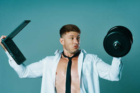 a man in a shirt with a pumped-up body laptop dumbbells business officeの写真素材