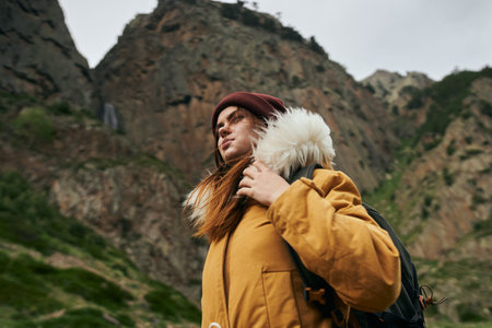 woman in a yellow jacket with a backpack in the mountains travel adventure