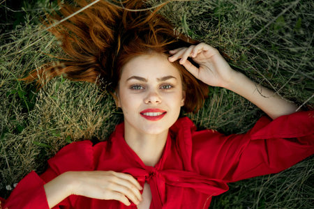 pretty woman in red dress lies on the grass landscape freedom