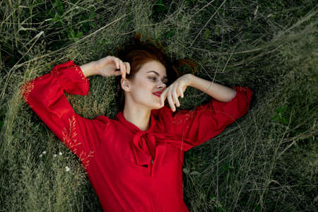 woman in red dress lies on the grass nature freedom summerの写真素材