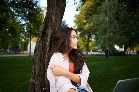 woman with laptop sitting on the grass business technologyの写真素材