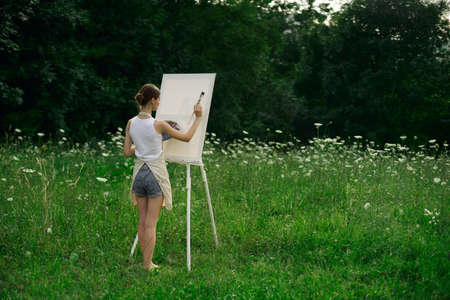 woman artist in aprons paint palette easel natureの写真素材