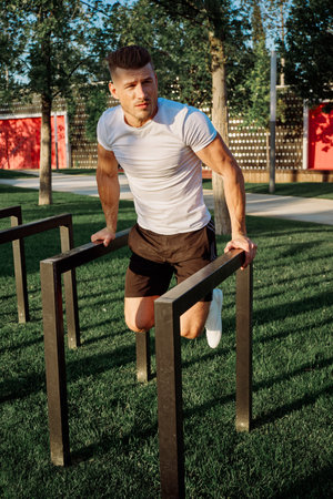 athletic man with dumbbells outdoors at CrossFit park